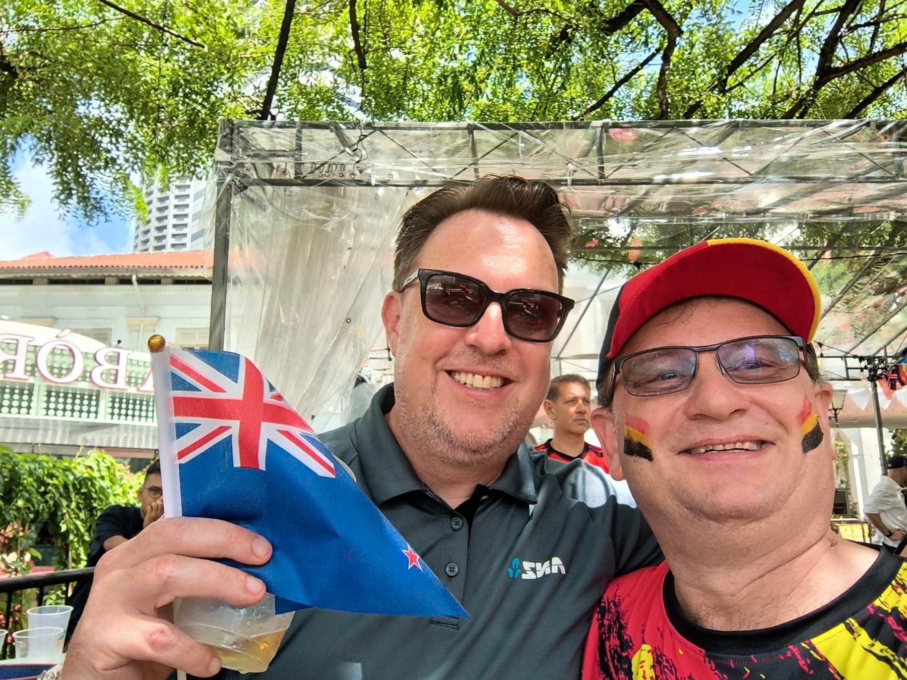 Two members with Belgian face paint holding a New Zealand flag at the FIFA World Cup screening